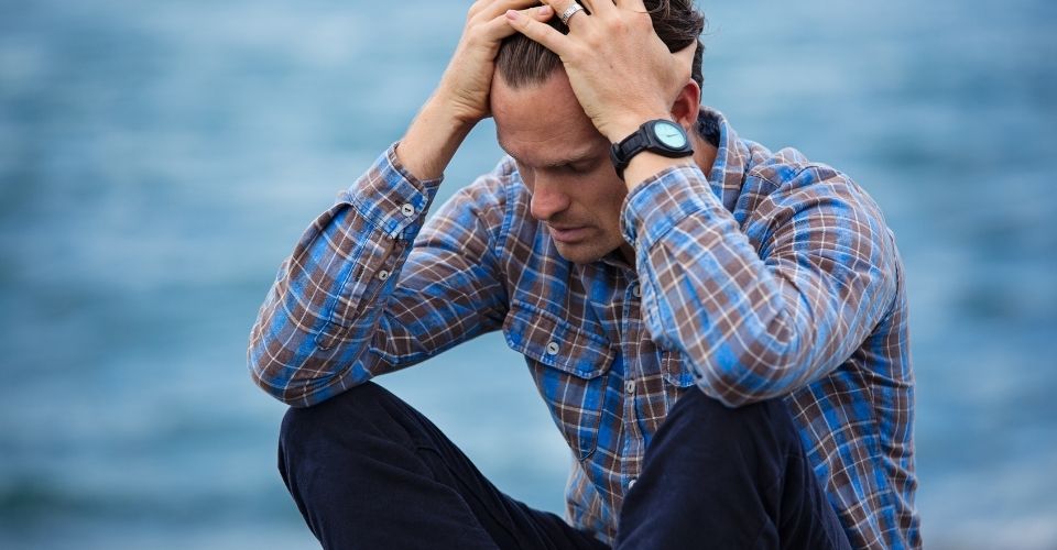 Man aan het water worstelt zichtbaar met zijn emoties – symbool voor de innerlijke strijd na een keuze die goed was voor hemzelf.