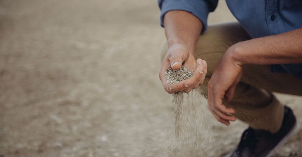 Hand laat zand los als symbool voor loslaten van controle en accepteren wat is om verder te kunnen