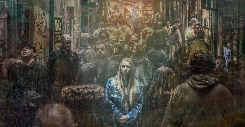 Vrouw die stil staat in drukke menigte – metafoor voor de bevriesreactie bij stress of overweldiging, zoals het konijn dat in de koplampen kijkt