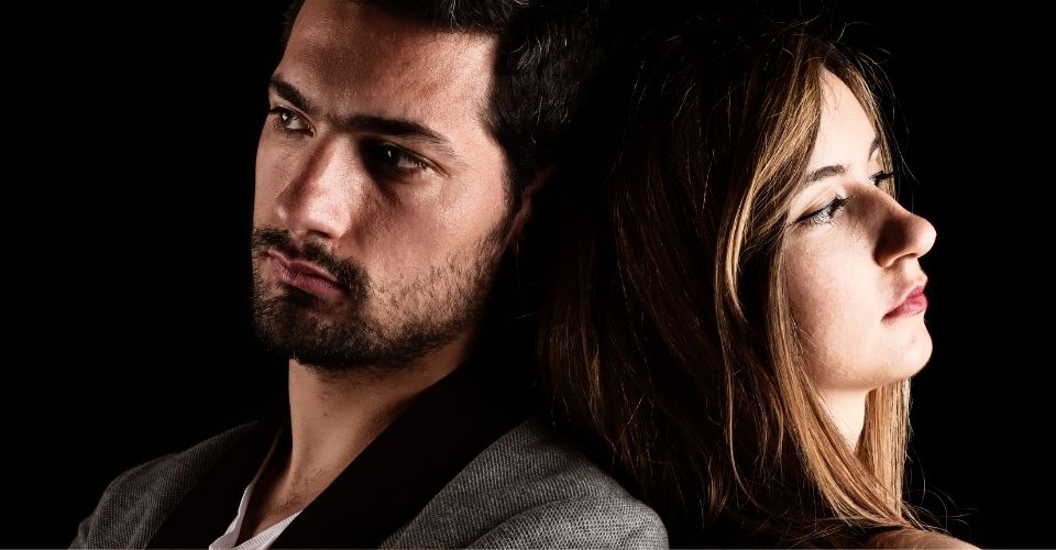 Man en vrouw zitten rug aan rug in stilte - illustratie van de impact van een relatietrauma en de noodzaak tot herstel en erkenning