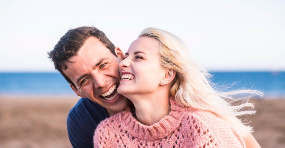 Lachend stel aan het strand – lachen en praten als sleutels tot een sterke, gezonde relatie vol verbinding en plezier.