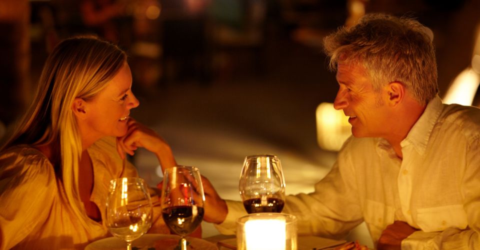 Stel zit samen aan tafel met kaarslicht, eten en wijn – intiem moment van quality time om de relatie te versterken.