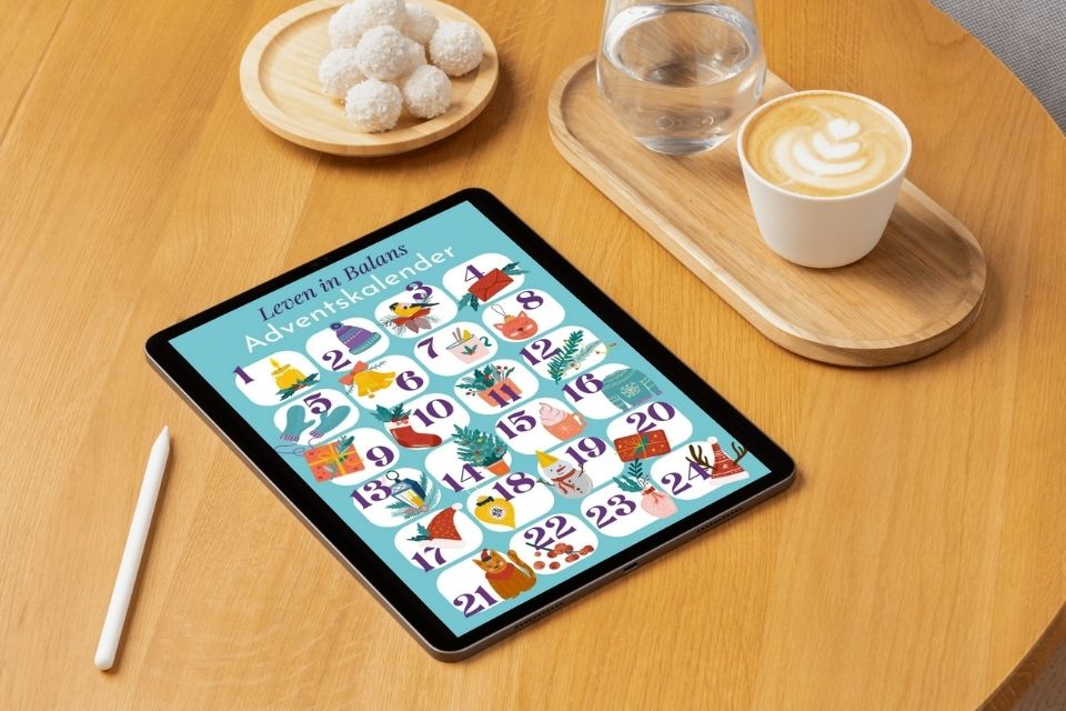 De Jouw Leven in Balans Adventskalender op een tablet naast een koffie en versnapering op een tafel