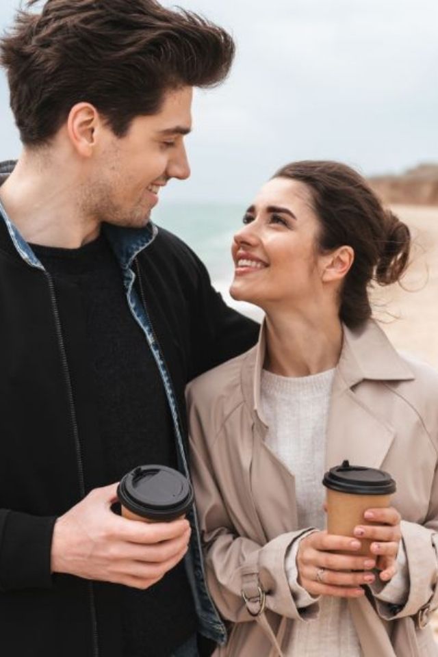 Man en vrouw kijken elkaar liefdevol aan tijdens een strandwandeling – kleine momenten van aandacht zorgen voor een sterke relatie.