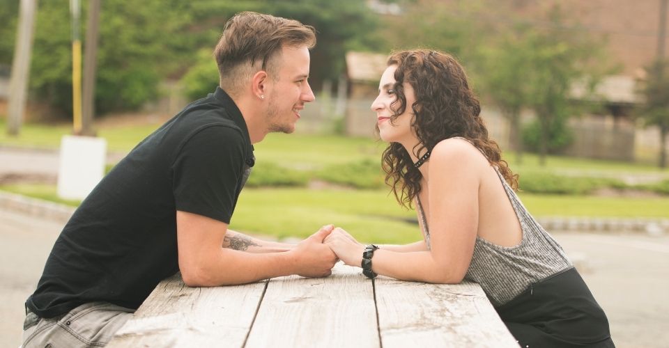 Stel kijkt elkaar liefdevol aan en houdt elkaars handen vast – beeld van gezien worden en erkenning geven in een relatie.