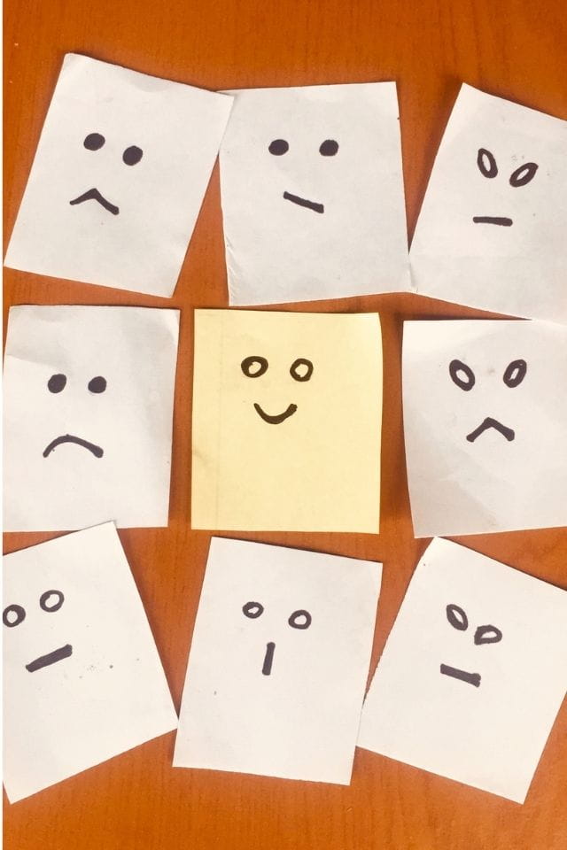 Verschillende getekende emotiegezichten op papier, met in het midden een vrolijk gezicht. De afbeelding laat zien hoe divers menselijke emoties zijn — iets wat ChatGPT niet kan waarnemen.